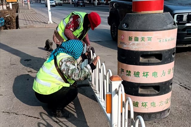 环卫工人在擦拭十字路口边的交通护栏.jpg